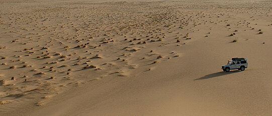 Jeep driving through a barren desert.