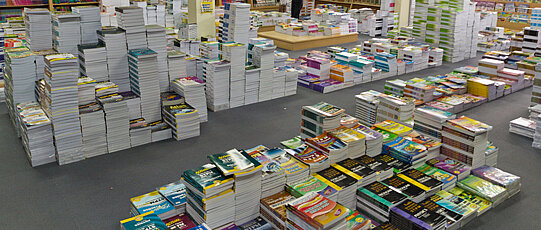 Verschieden große Bücherstapel in einer Halle.