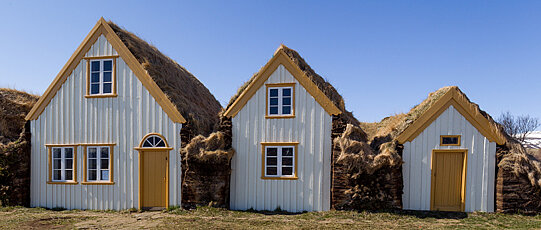 Three yellow-white houses standing side by side and getting smaller from left to right.