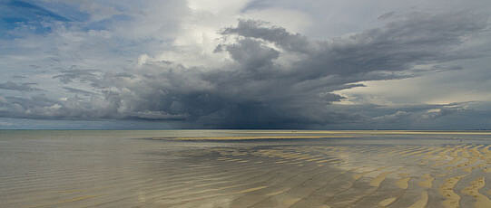 Seichtes Meeresufer mit Wolken am Himmel.